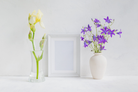 Mockup with a white frame and summer flowers in a vase on a light backgroundの写真素材