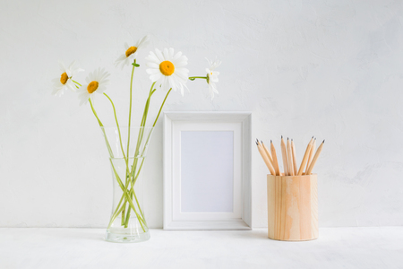 Home interior with decor elements. White frame, flowers in a vase, pencilsの写真素材