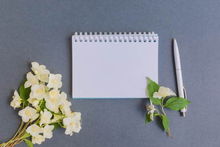 Mockup notebook with white jasmine flowers and dark background empty space for your text, top viewの写真素材