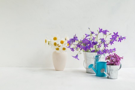 Home interior and garden concept with summer flowers in a metal bucket on a light backgroundの写真素材