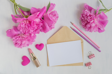 Mockup white greeting card and envelope with pink peonies on a light backgroundの写真素材