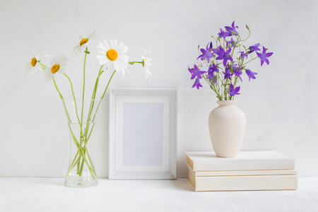 Home interior with decor elements. White frame, flowers in a vase, books and pencilsの写真素材
