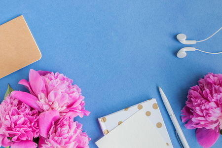 Flat lay desk with pink peonies on a blue backgroundの写真素材