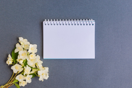 Mockup notebook with white jasmine flowers and dark background empty space for your text, top viewの写真素材