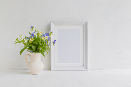 Mockup with a white frame and summer flowers in a vase on a light backgroundの写真素材