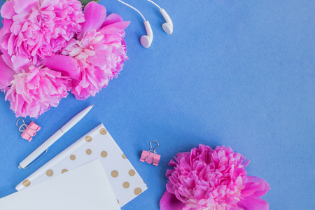 Flat lay desk with pink peonies on a blue backgroundの写真素材