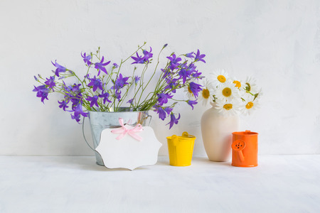 Home interior and garden concept with summer flowers in a metal bucket on a light backgroundの写真素材