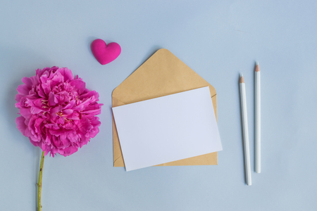 Mockup white greeting card and envelope with pink peony on a light blue backgroundの写真素材
