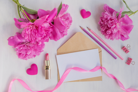 Mockup white greeting card and envelope with pink peonies on a light backgroundの写真素材