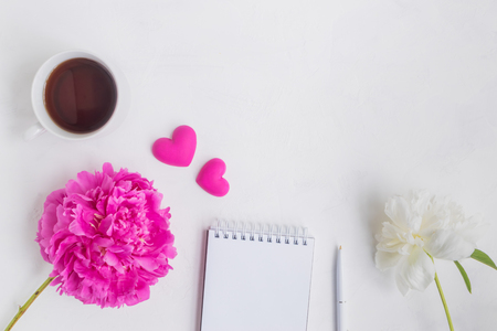 Flat lay desk with pink peony, notebook and accessories on light backgroundの写真素材