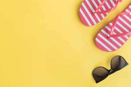 Flip flops and sunglasses on a yellow background. Top view, flat layの写真素材