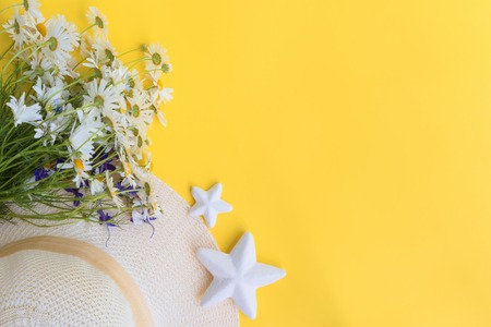 Summer hat and flowers on a yellow background. Top view, flat layの写真素材
