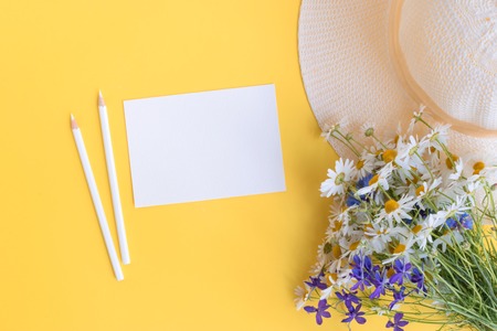 Mockup white greeting card with summer hat and flowers on a yellow backgroundの写真素材