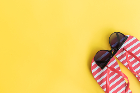 Flip flops and sunglasses on a yellow background. Top view, flat layの写真素材