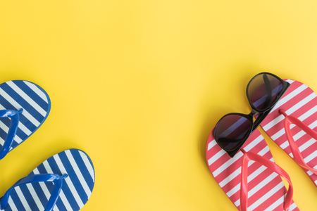 Flip flops and sunglasses on a yellow background. Top view, flat layの写真素材