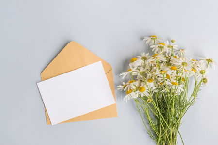 Mockup white greeting card and envelope with white daisie on a light blue backgroundの写真素材