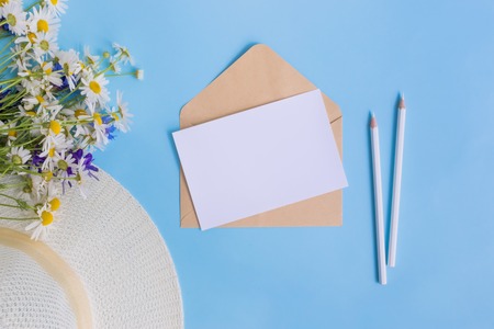 Mockup white greeting card and envelope with summer flowers on a blue backgroundの写真素材