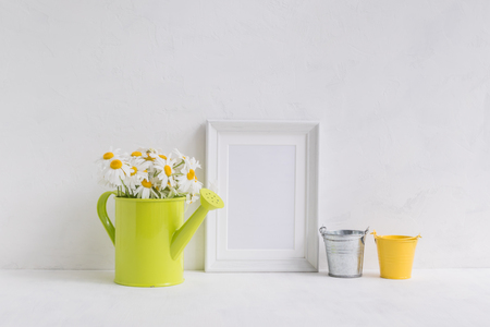 Mockup with a white frame and white daisies in ain a metal watering can on a light backgroundの写真素材