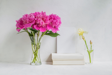 Home interior with decor elements. White frame, flowers in a vase, booksの写真素材