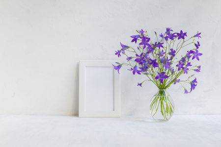 Mockup with a white frame and summer flowers in a vase on a light backgroundの写真素材