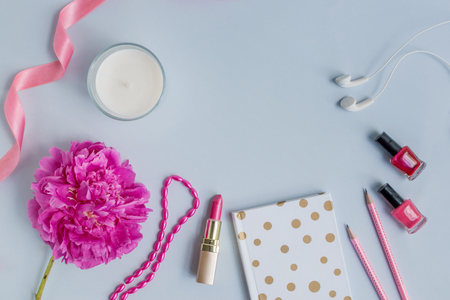Flat lay desk with pink peony, cosmetics and accessories on blue backgroundの写真素材