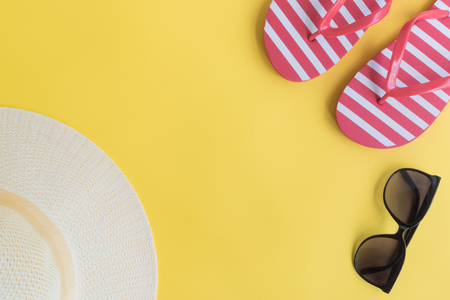 Summer hat, flip flops and sunglasses on a yellow background. Top view, flat layの写真素材