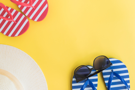 Summer hat, flip flops and sunglasses on a yellow background. Top view, flat layの写真素材