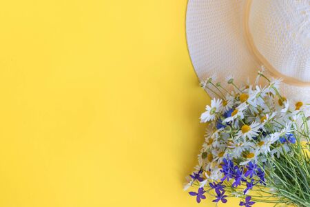 Summer hat and flowers on a yellow background. Top view, flat layの写真素材