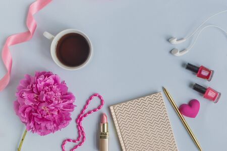 Flat lay desk with pink peony, cosmetics and accessories on blue backgroundの写真素材