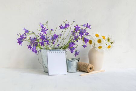 Home interior and garden concept with summer flowers in a metal bucket on a light backgroundの写真素材