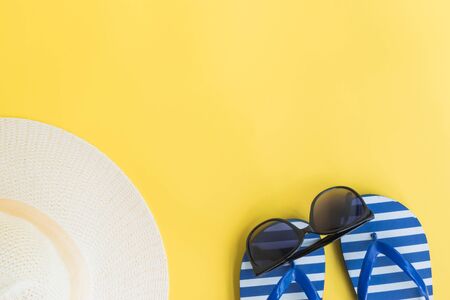 Summer hat, flip flops and sunglasses on a yellow background. Top view, flat layの写真素材