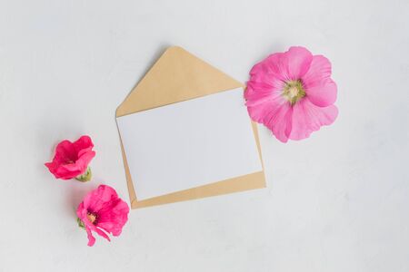 Mockup white greeting card and envelope with pink flowers on a  light backgroundの写真素材