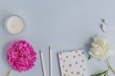 Flat lay desk with pink peony, cosmetics and accessories on blue backgroundの写真素材