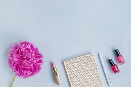 Flat lay desk with pink peony, cosmetics and accessories on blue backgroundの写真素材