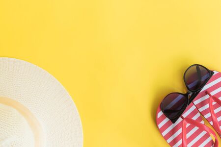 Summer hat, flip flops and sunglasses on a yellow background. Top view, flat layの写真素材