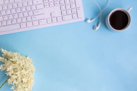 Blogger or freelancer workspace with white flower hydrangea on blue backgroundの写真素材