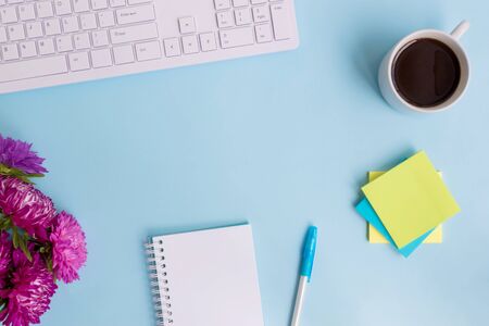 Blogger or freelancer workspace with notebook and pink flowers on blue backgroundの写真素材