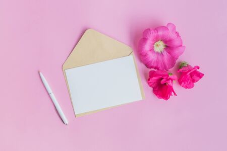 Mockup white greeting card and envelope with pink flowers on a pink backgroundの写真素材