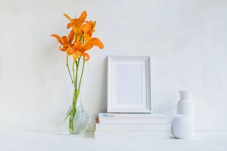 Home interior with decor elements. White frame, flowers in a vase and booksの写真素材