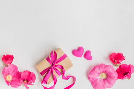 Flat lay desk with pink flowers and gift on light backgroundの写真素材