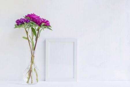 Mockup with a white frame and pink flower in a vase on a light backgroundの写真素材