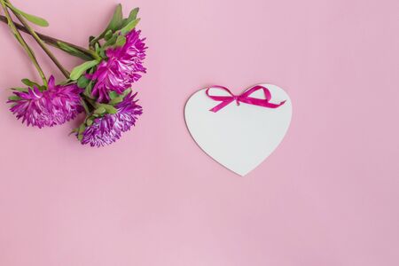 Bouquet with pink flowers and white heart on pink background empty space for your text, top viewの写真素材