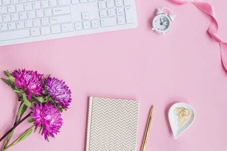 Blogger or freelancer workspace with notebook and pink flowers on pink backgroundの写真素材