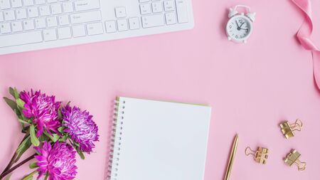 Blogger or freelancer workspace with notebook and pink flowers on pink backgroundの写真素材