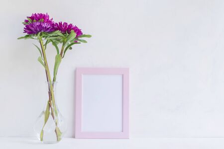 Mockup with a pink frame and pink flower in a vase on a light backgroundの写真素材