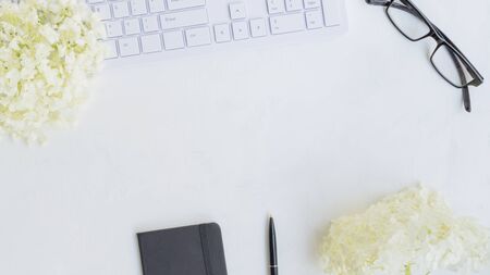Blogger or freelancer workspace with notebook and white flower hydrangea on light backgroundの写真素材