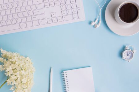 Blogger or freelancer workspace with notebook and white flower hydrangea on blue backgroundの写真素材