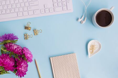Blogger or freelancer workspace with notebook and pink flowers on blue backgroundの写真素材