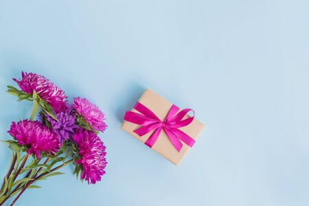 Bouquet with pink flowers with gift box on blue background empty space for your text, top viewの写真素材