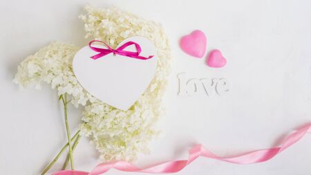 White flower hydrangea and pink hearts on a light background with letters loveの写真素材